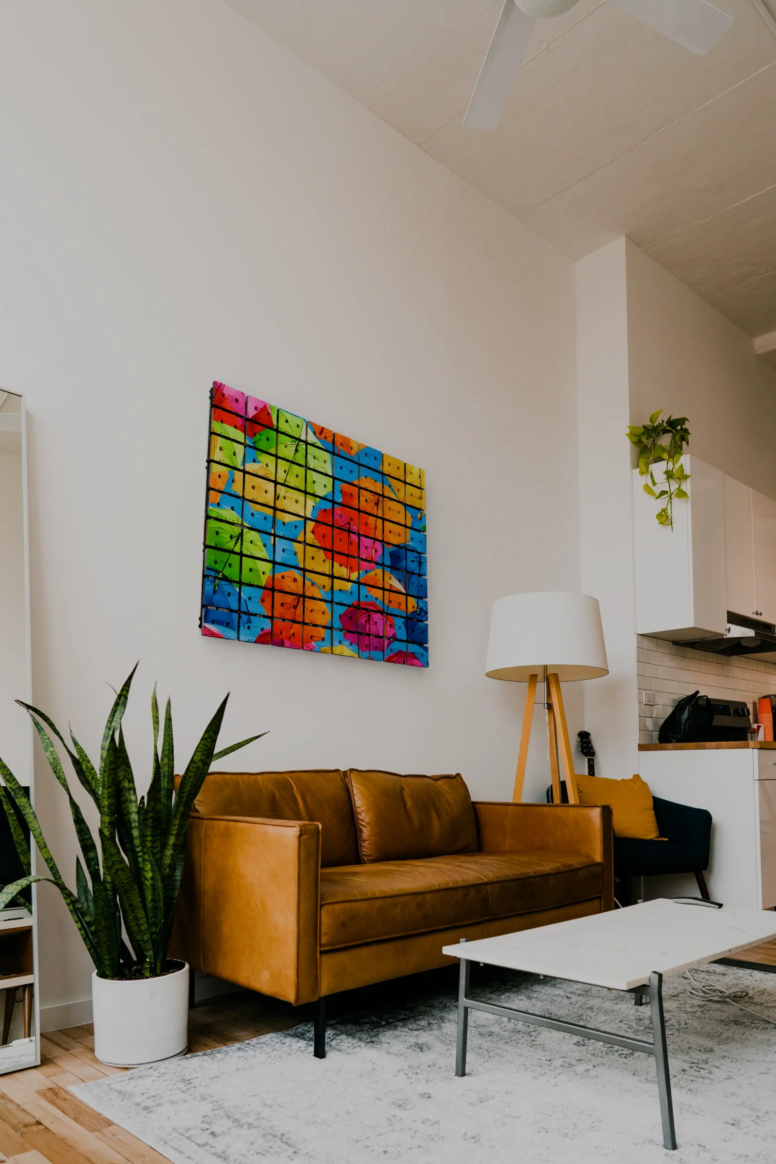 Colorful umbrella cassette mosaic displayed above a brown leather sofa